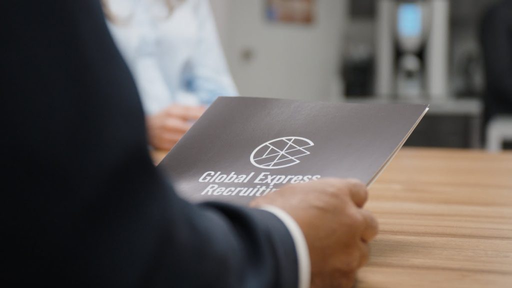 Person holding a Global Express Recruiting document, representing the advisory process for choosing between M-1 and F-1 visas.