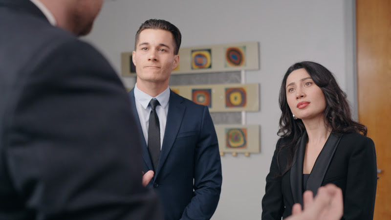 A couple dressed in business attire attentively listening to a conversation, possibly during an immigration interview or consultation.