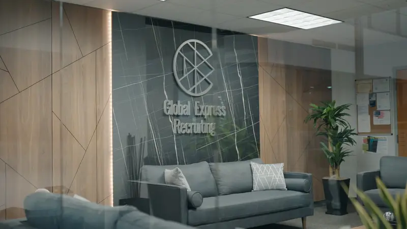 global express recruiting professional office facilities in the USA. Global Express Recruiting office reception area featuring company logo on the wall and grey sofas.
