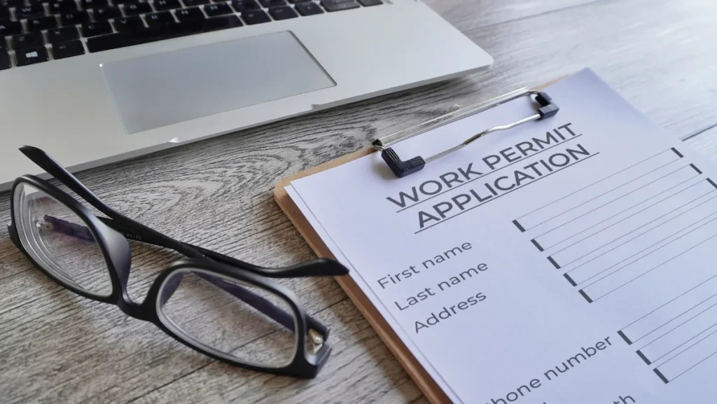 Work permit usa application form on a clipboard with reading glasses and a laptop